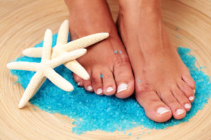 sexy female feet with bath salt and shells - beauty treatment